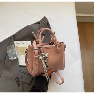 Detail of pink lychee leather bucket bag with silver heart charm and adjustable strap