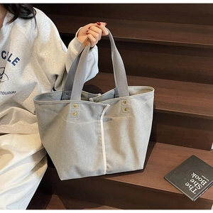 Detail of grey canvas tote bag with contrast stitching and decorative copper rivets