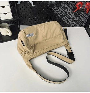 Detail of khaki canvas messenger bag with brand patch and velcro front pocket