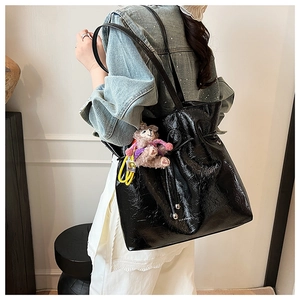Détail du sac cabas en cuir verni brillant noir avec cordon et pendentif en peluche