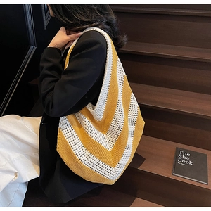 Detail of yellow and beige knit tote bag with V-shaped stripe pattern on a shoulder
