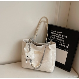 Detail of white tote bag with snake skin texture, silver chains and pearl charms