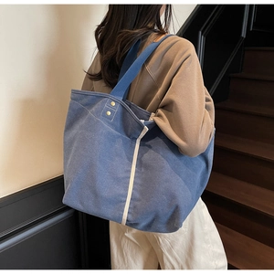 Detail view of large blue canvas tote bag showing textured fabric and side stripe accent
