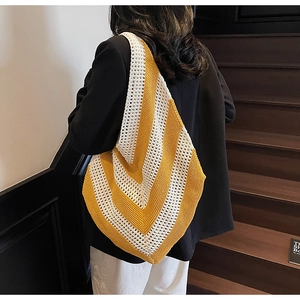 Detail of a large knitted tote bag with yellow and white V-shaped stripes on shoulder