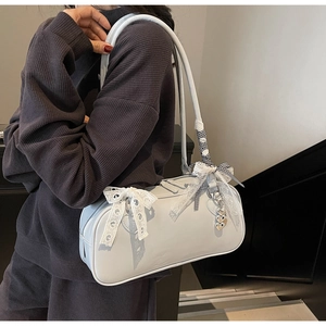 Detail of light blue Boston bag with lace bow, ribbon strap and gold bear charm