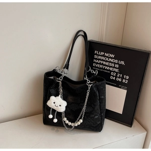 Close-up of black snakeskin tote bag with silver chain, pearls and cloud charm
