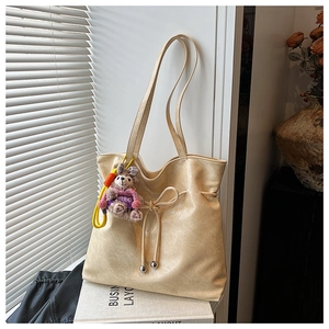 Détail du sac cabas beige en cuir froissé avec nœud coulissant et breloque peluche