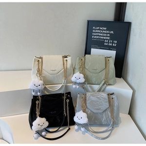 Detailed display of four textured leather shoulder bags in beige green black and grey