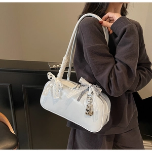 Detail of light blue glossy shoulder bag featuring white lace bow and heart metal pendant