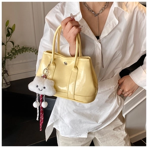 Close-up of bright yellow patent leather handbag with a plush cloud charm detail