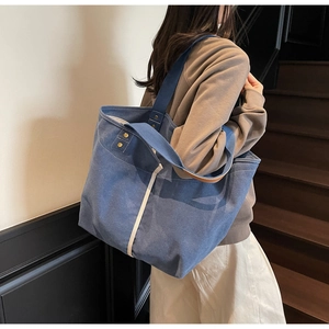 Detail of blue canvas tote bag with reinforced straps and white contrast stitching