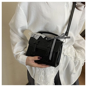 Detail of black satchel bag featuring star patches and lace ribbon bow accessories