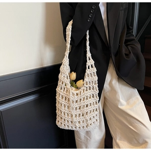 Detalle del bolso de cubo blanco roto tejido a mano con textura de malla y tulipanes de adorno