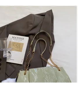 Detail of light green crossbody bag featuring glossy crinkled texture and gold chain strap