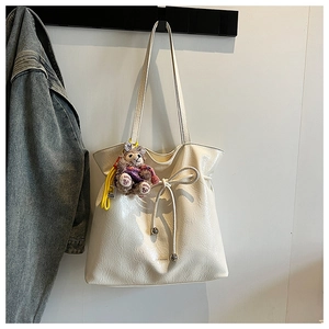 Détail du cabas en cuir verni blanc crème avec nœud de serrage et pendentif en peluche
