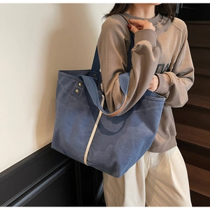 Detail of navy canvas tote bag with beige vertical stripes and reinforced metal rivets