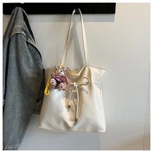 Détail d'un sac cabas matelassé blanc avec nœud de serrage et breloque en peluche