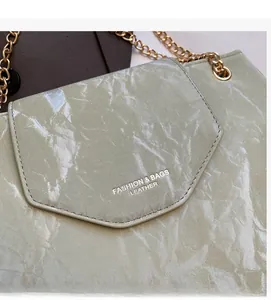 Detailed shot of green pleated leather texture and gold chain on the shoulder bag
