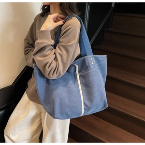 Close-up of durable navy canvas tote bag with cream straps and gold metal rivets