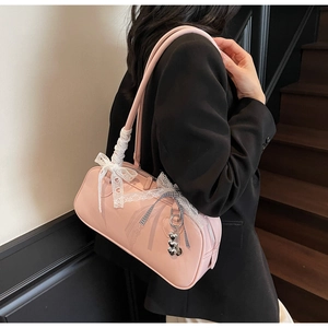 Close-up of pink underarm Boston bag with lace bow, ribbon, and silver heart pendant