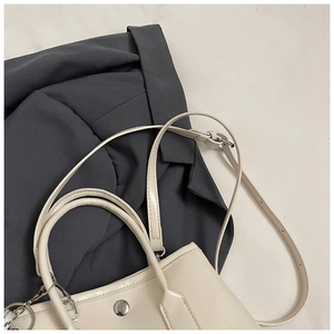 Detail view of cream PU leather handbag with dual handles and metal adjustable strap