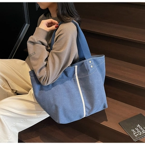 Detail of dark blue canvas tote bag with wide fabric handles and metallic eyelet accents