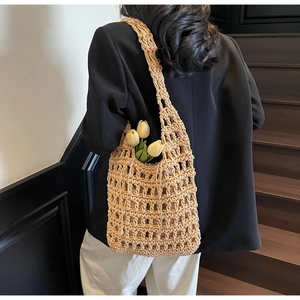 Detalle del tejido de un bolso de paja beige llevado por una modelo con chaqueta negra
