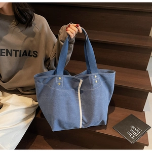 Blue canvas tote bag detail with navy handles, metal rivets and large capacity interior