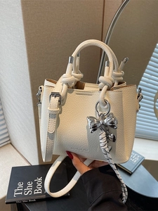 Elegant cream-colored bucket bag in litchi leather with silver bow charm and top handles