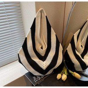 Close-up of black and white V-patterned knit shoulder bag with hollow mesh texture