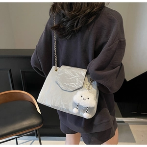 Detail of grey chain shoulder bag with oil wax texture and cloud plush charm decoration