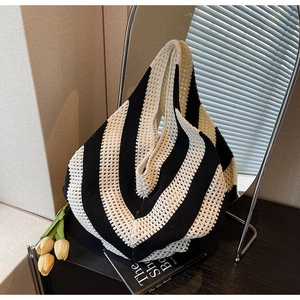 Detail of black and white striped knitted tote bag with textured hollow weave pattern