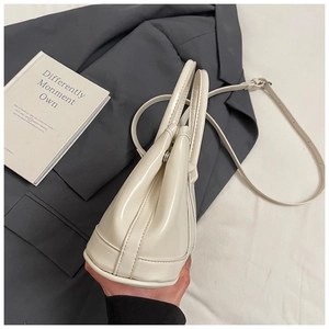 Detailed side view of beige vegan leather handbag with sturdy base and adjustable strap