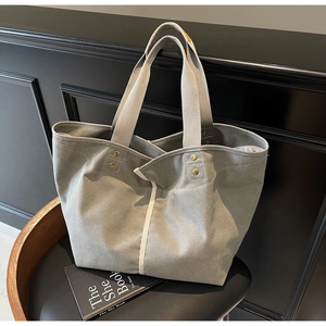 Detail of grey canvas tote bag with contrast white piping and gold rivet handle
