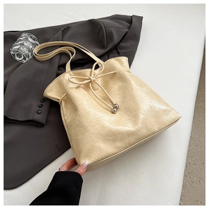 Détail du sac seau crème montrant le cuir texturé et les perles métalliques argentées