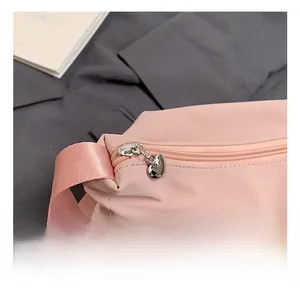 Detail show of pink crossbody bag with silver heart-shaped metal zipper and nylon texture