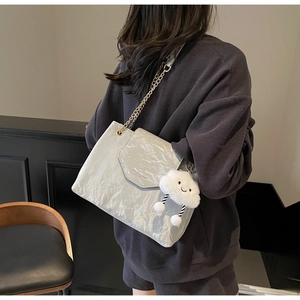 Close-up of trendy silver pleated shoulder bag with gold chain and white cloud charm