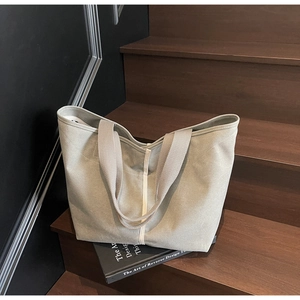 Detail of grey-green canvas tote bag with white strap on wooden stairs for daily commute