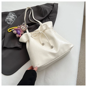 Gros plan du sac fourre-tout blanc avec texture plissée et nœud sur une veste grise