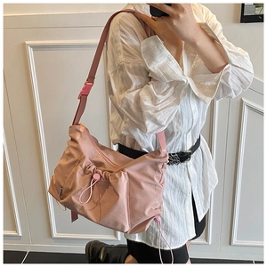 Detailed view of mauve nylon crossbody bag with adjustable strap and side drawstring
