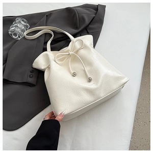 Détail du sac seau à cordon crème montrant le cuir plissé brillant et les embouts en métal