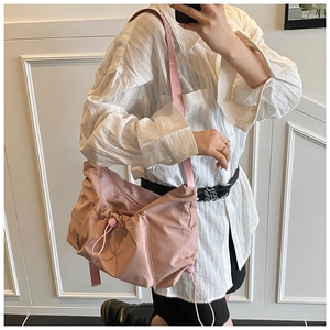Detail of light pink nylon tote bag with drawstring pleated pocket and adjustable strap