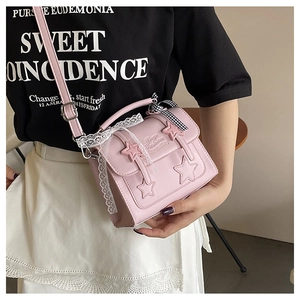 Detail of pink messenger bag with 3D star charms, lace trim and checkered bow accent