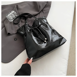 Vue macro d'un sac cabas en cuir verni noir avec texture ondulée et cordon de serrage