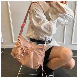 Pink nylon tote bag detail showing drawstring pleats and adjustable strap on a model