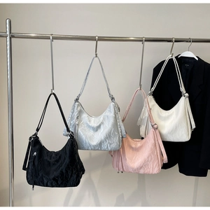 Detail showing four colored hobo bags with pleated texture hanging on a metal rack
