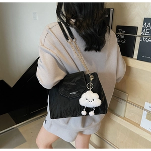 Detail of black pleated shoulder bag with gold chain strap and cute cloud charm