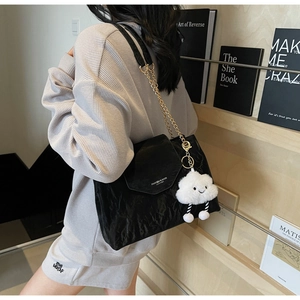 Detail of black wrinkled leather tote with gold chain strap and cloud plush charm