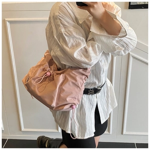 Detail of pink pleated nylon tote bag with drawstring side and water-resistant texture