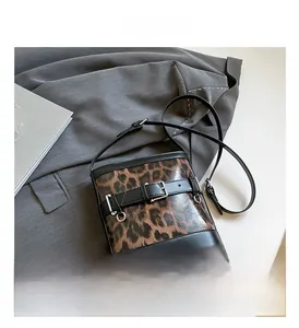 Detail of leopard print bucket bag with black belt buckle and adjustable strap